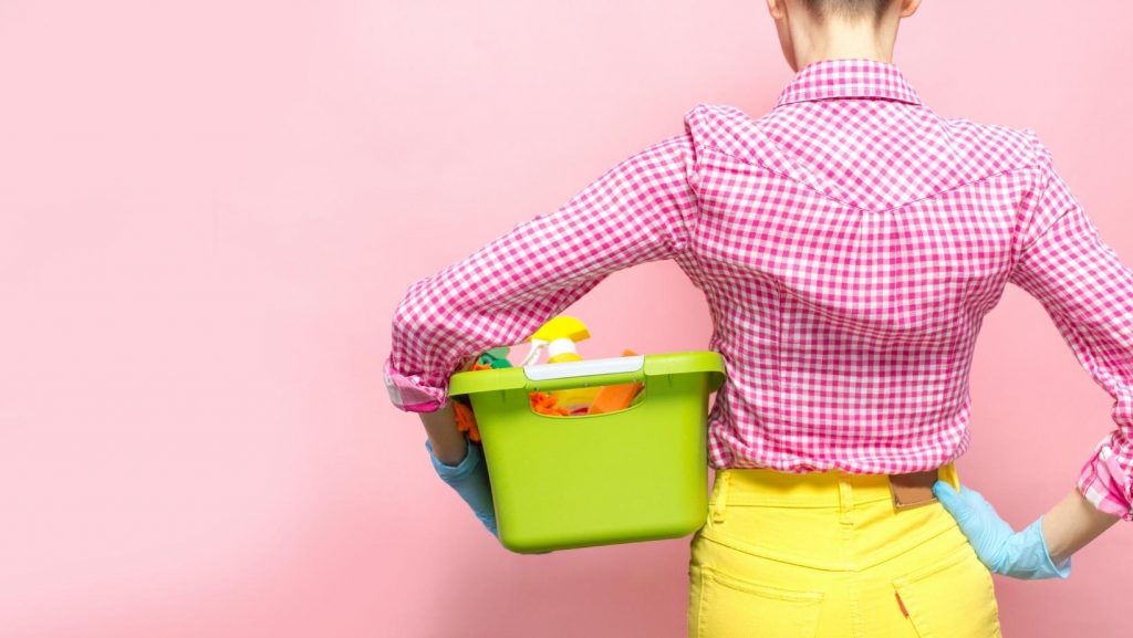 a woman in a pink and white checkered shirt holding a green box.