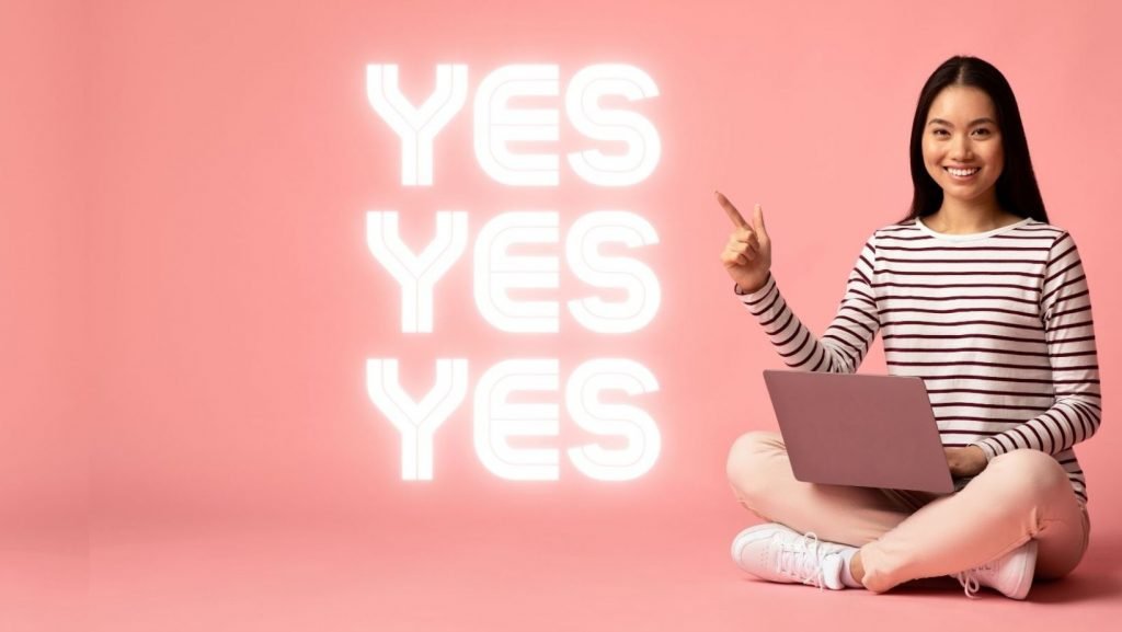 Girl sitting with laptop pointing to yes in answer to do you need a website