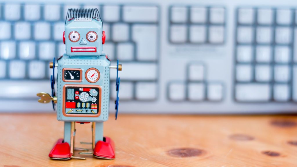 a ChatGPT toy robot sitting in front of a keyboard.