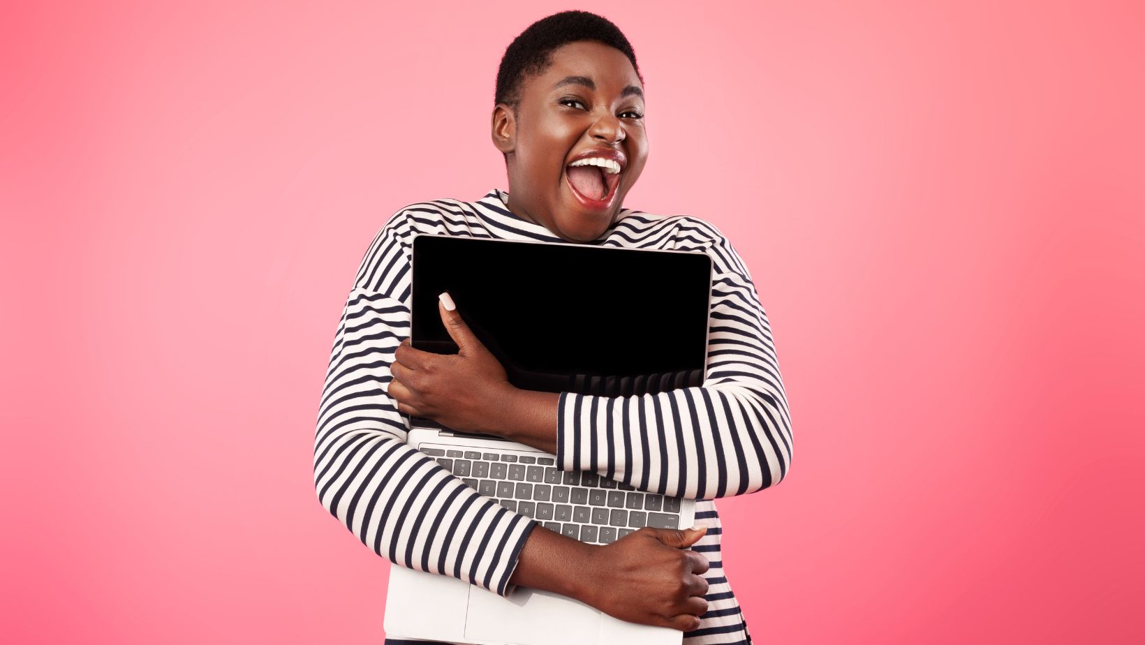 A happy woman holding a laptop and smiling because she's using the best website platform