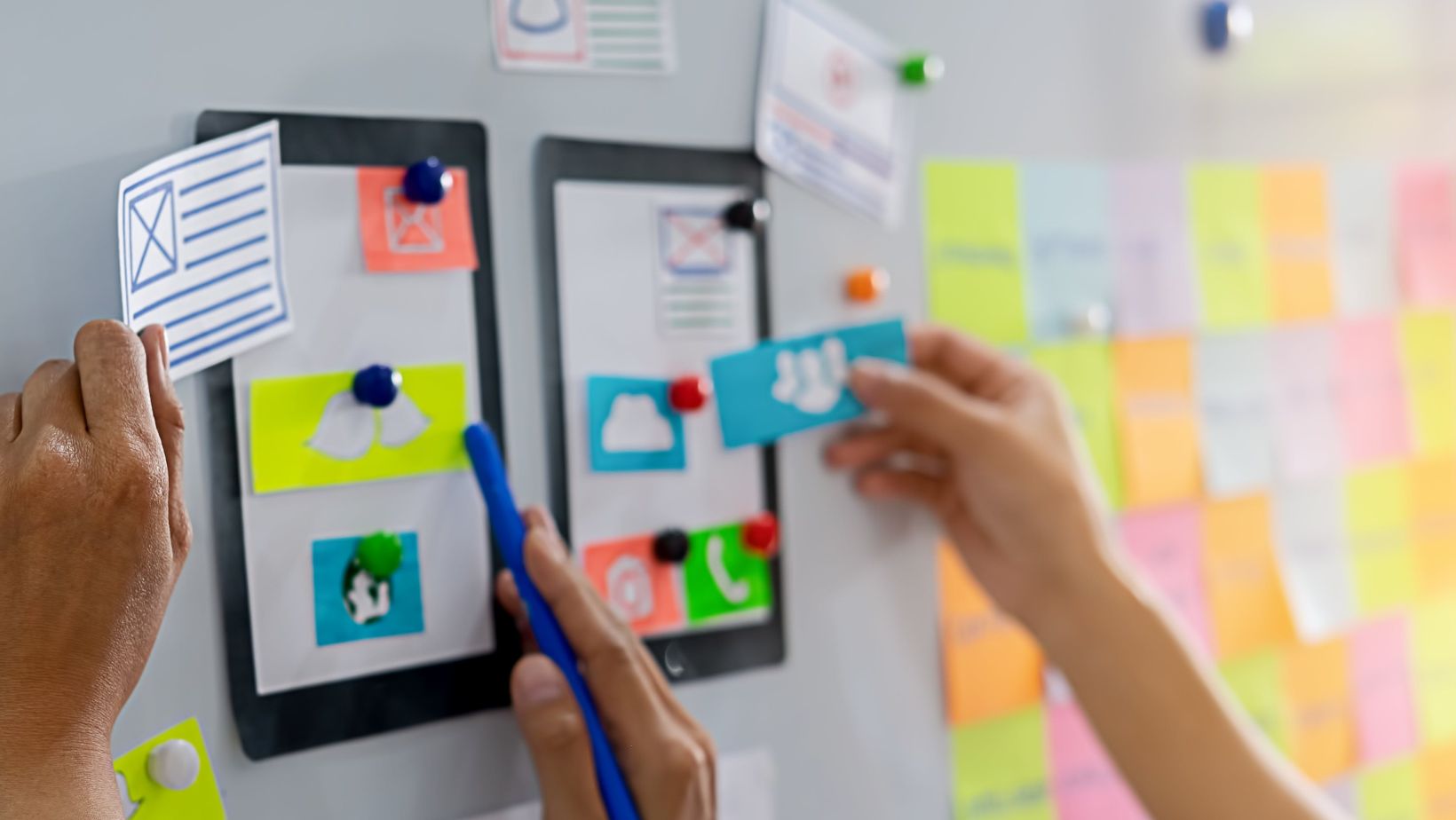 Individuals adding sticky notes to a vertical surface. Elements to include in an effective website design