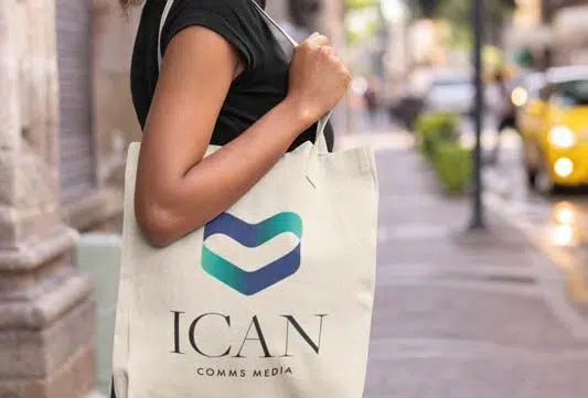 A woman carrying a tote bag with the logo ican representing services.