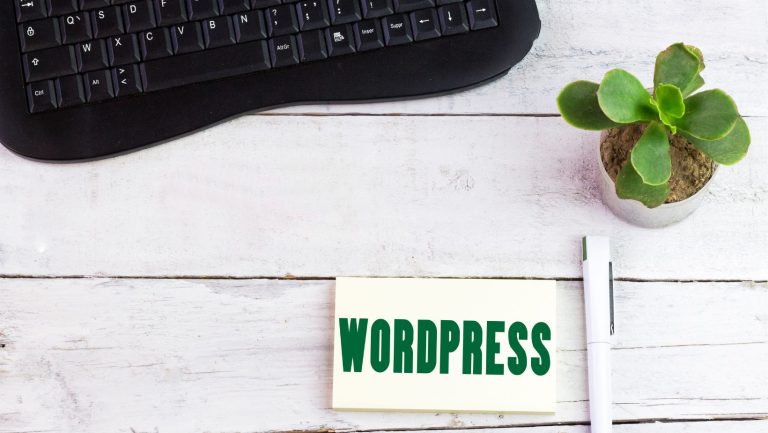 A black keyboard, a potted plant, and a pen next to a card with the text "WordPress Toolbar" on a white wooden table.