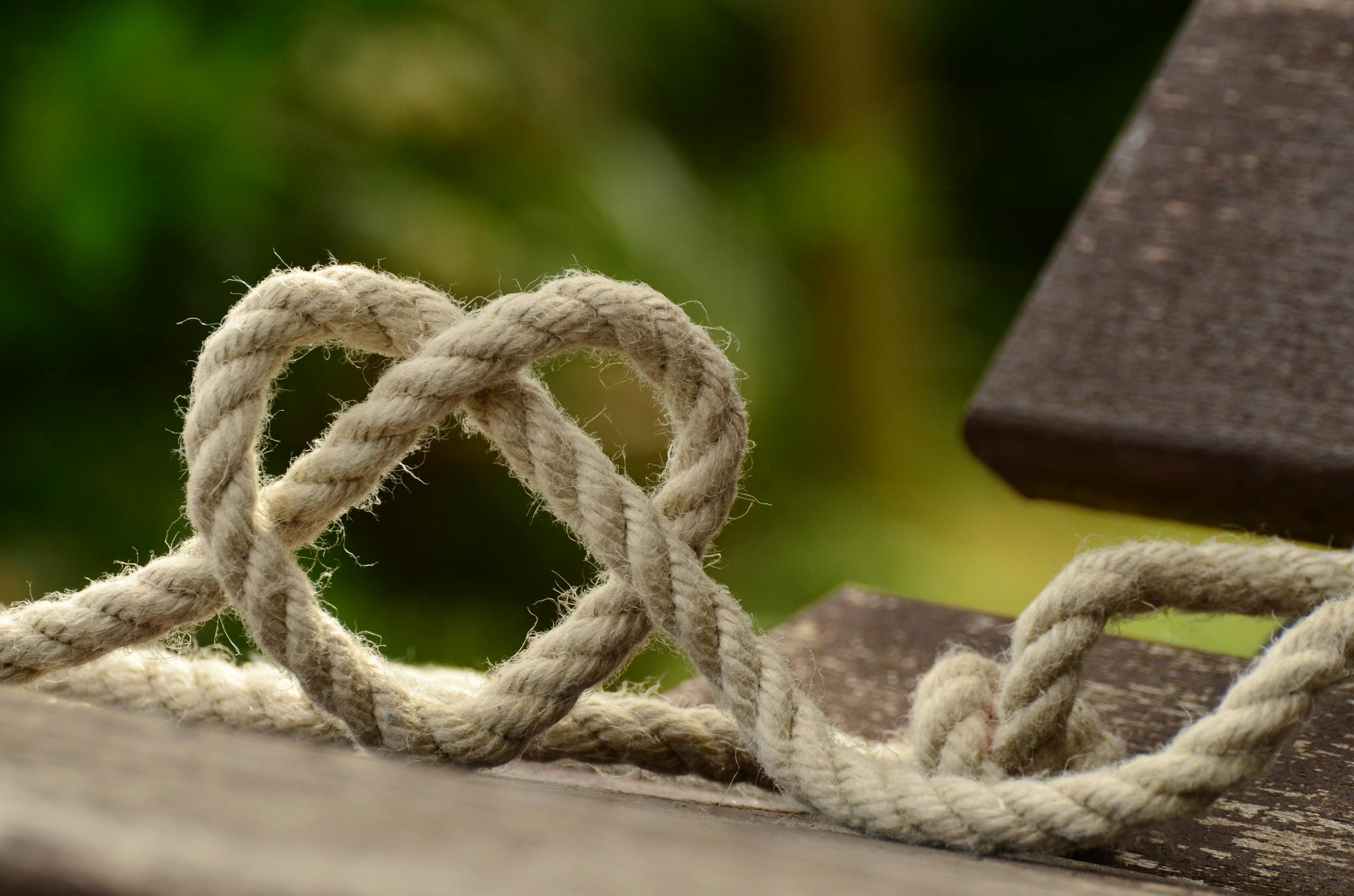 Close-up of twine forming a heart shape on a rustic wooden table outdoors to depict Connect - website visibility systems.